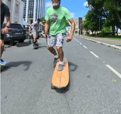 Membro da crew sorrindo andando de longboard